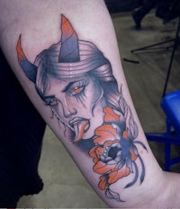a tattoo of a woman with horns and flowers