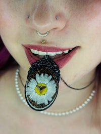 a woman wearing a necklace with a daisy on it