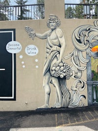 a mural on the side of a building with a man holding a bottle of wine