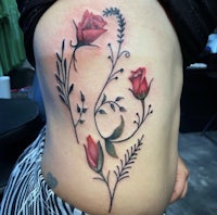 a woman with a tattoo of red roses on her stomach