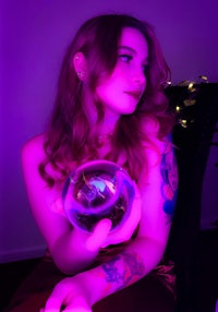 a woman with tattoos holding a crystal ball