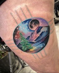 a woman's thigh tattoo with a mountain and moon