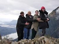 a group of people posing on top of a mountain