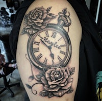 a tattoo with a clock and roses on the arm