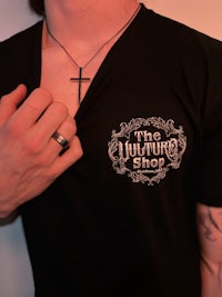 a man wearing a black t - shirt with a cross on it