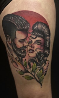 a tattoo of a man and woman with leaves on their thigh