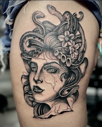 a tattoo of a woman with snakes on her thigh