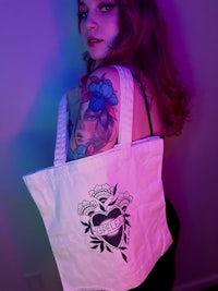a woman with tattoos holding a tote bag