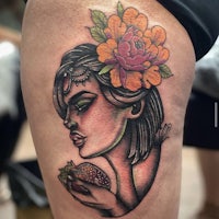 a tattoo of a woman with flowers on her thigh