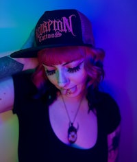a woman with tattoos and tattoos wearing a hat