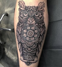 an owl tattoo on a man's forearm