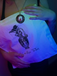 a woman holding a tote bag with a tattoo on it