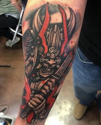 a samurai tattoo on a man's forearm